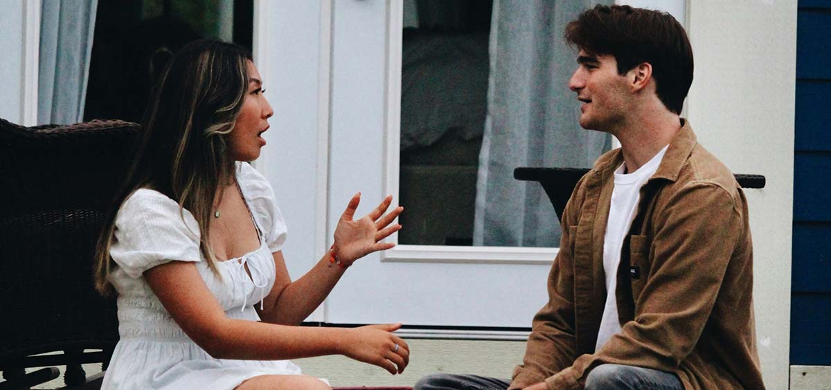 Deux personnes discutant sur une terrasse en bois, illustrant les échanges entre voisins et la gestion des limites de propriété.