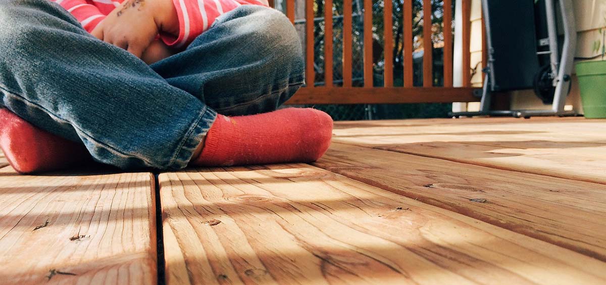 Personne assise sur une terrasse en bois, illustrant les enjeux d’intimité et d’exposition visuelle entre voisins.