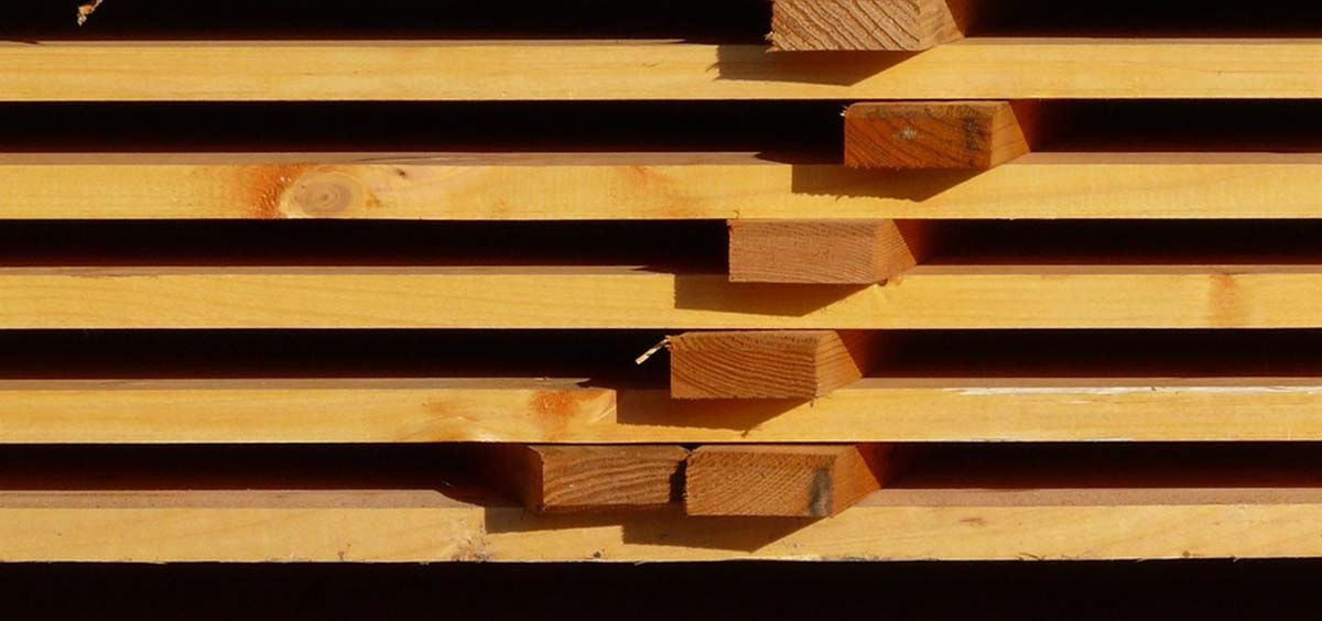 Lames de bois empilées pour la construction d’une terrasse, montrant la texture et la qualité du matériau.
