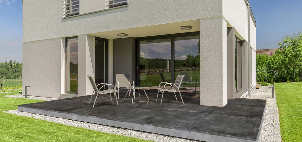 Terrasse en grès cérame avec espace détente, fauteuils confortables et aménagement extérieur contemporain.