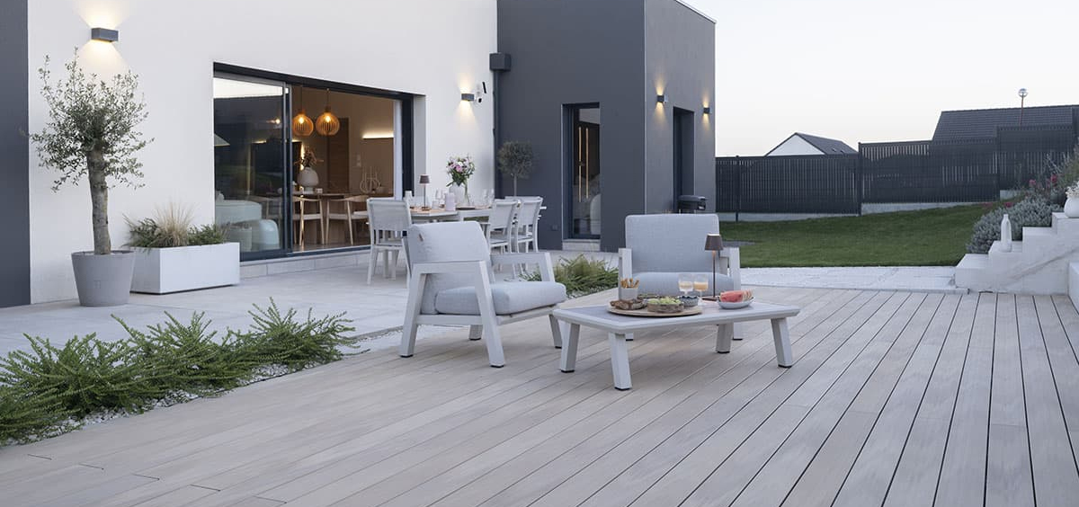 Terrasse composite moderne avec mobilier design et maison contemporaine, illustrant le confort et la simplicité du matériau.
